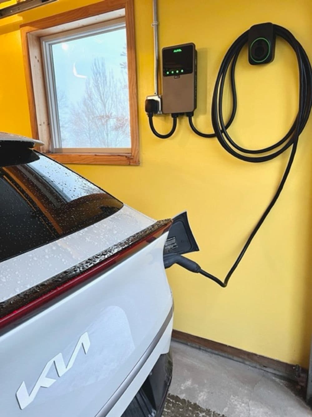 Electric vehicle charging at home with a wall-mounted charger in a bright yellow garage.