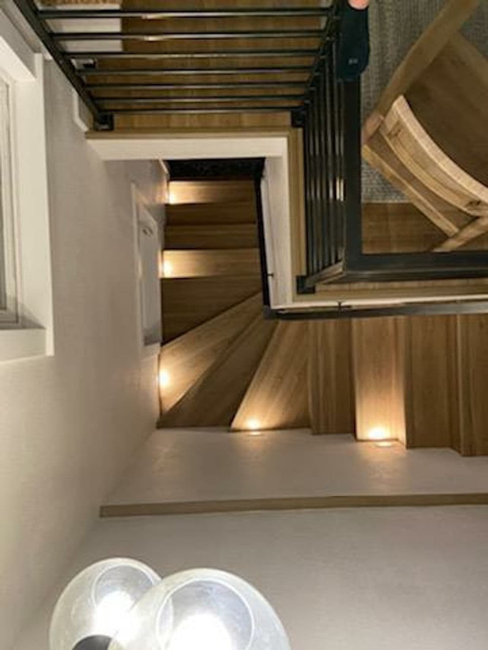Top view of wooden staircase with LED lights, modern decor, and stylish railing.