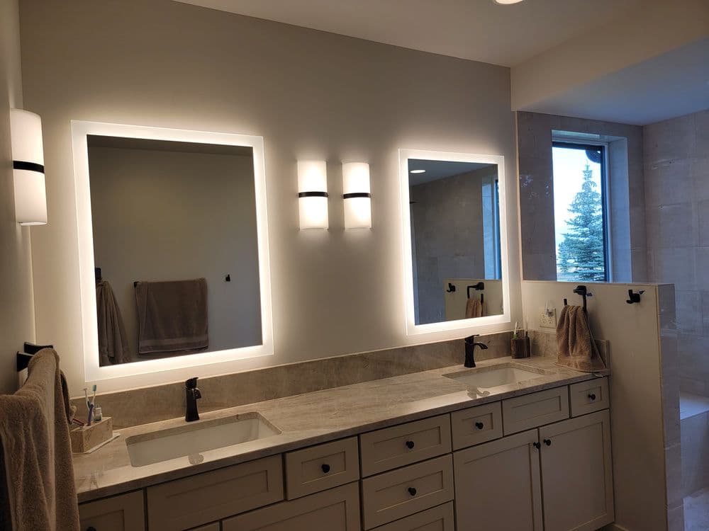 Modern bathroom with dual illuminated mirrors, elegant countertops, and stylish fixtures.