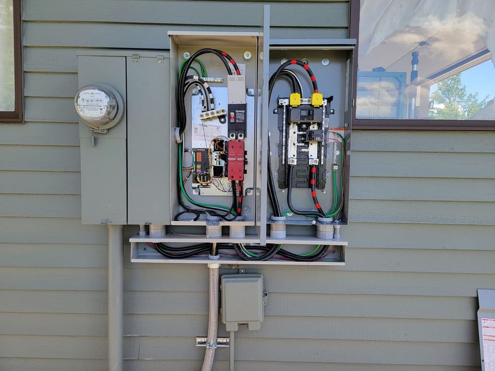 Electrical service panel with circuit breakers and utility meter on a residential building.