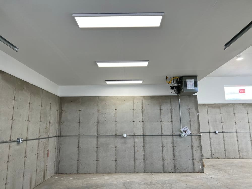 Modern garage interior with LED lighting, concrete walls, and overhead door opener.