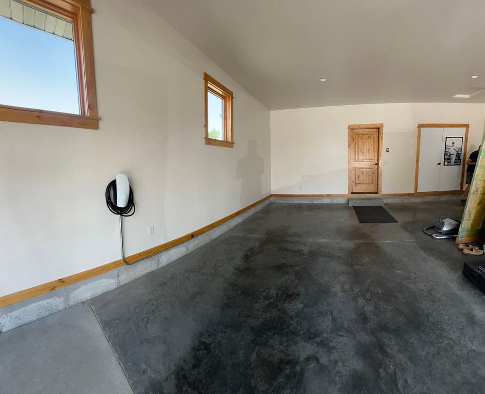 Spacious garage interior with concrete flooring and wall-mounted EV charger.