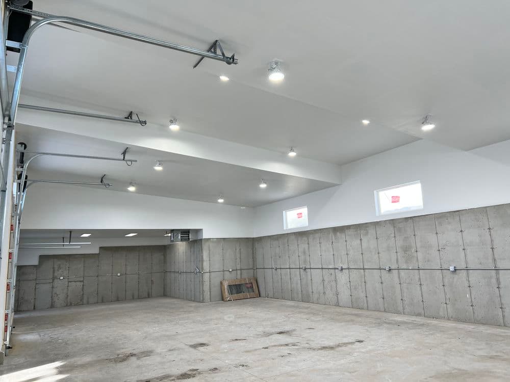 Spacious industrial-style garage with bright lighting and concrete walls, clear floor space.