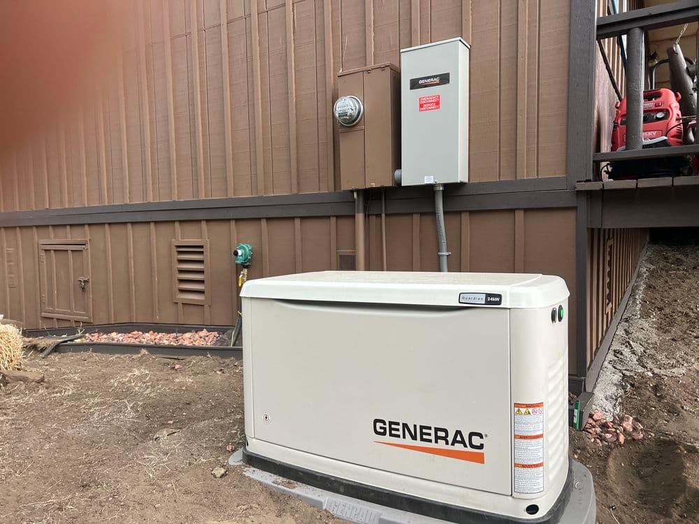 Generac outdoor generator installed beside a brown house with electrical meter and panel.