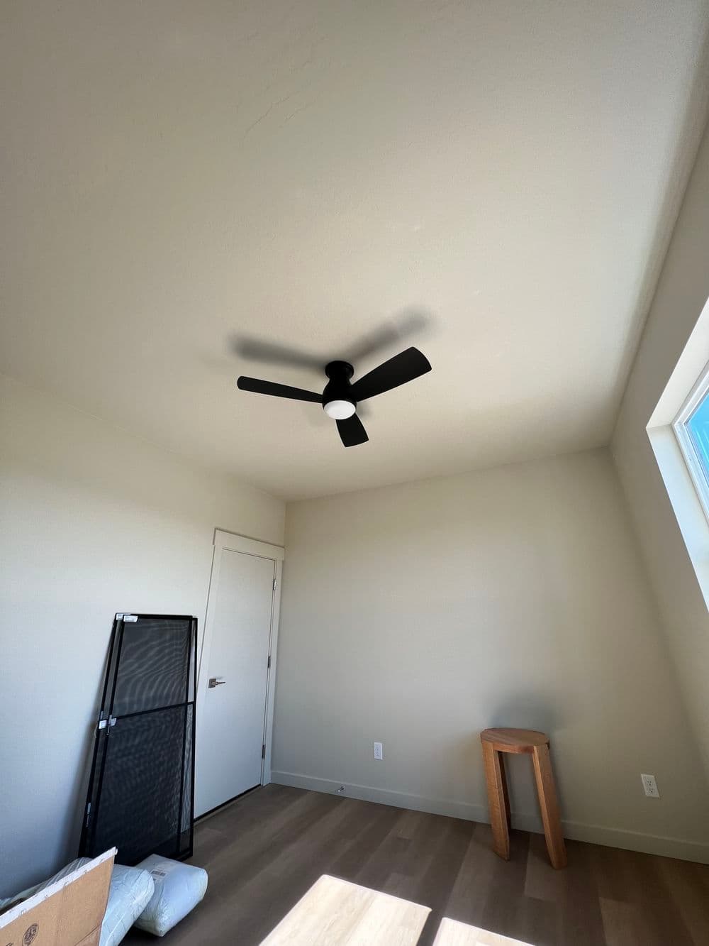 Modern room interior with a ceiling fan, light wooden flooring, and minimalist decor.