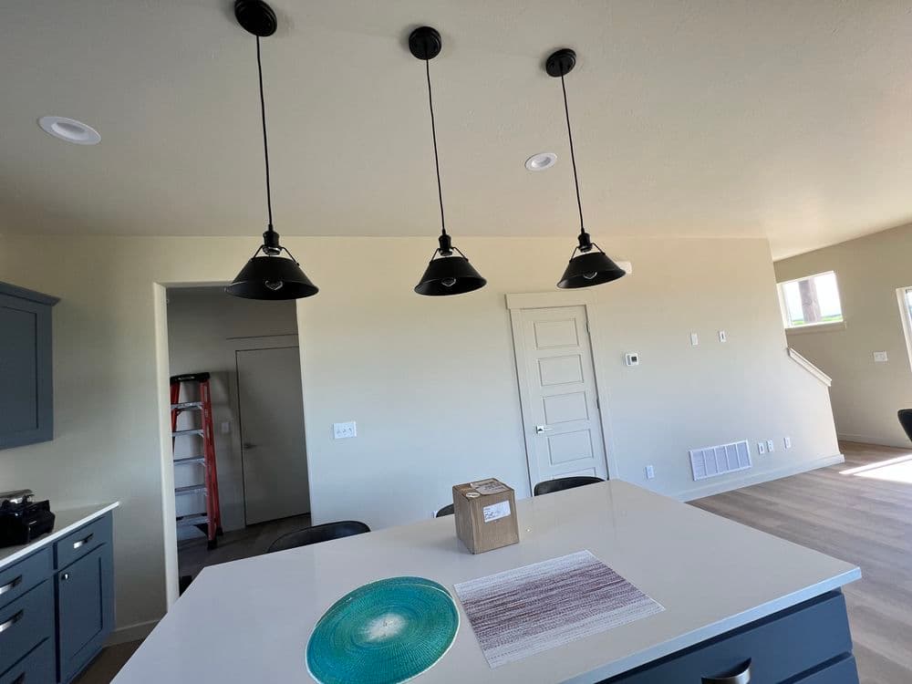 Modern kitchen with three pendant lights above an island and a package on the counter.