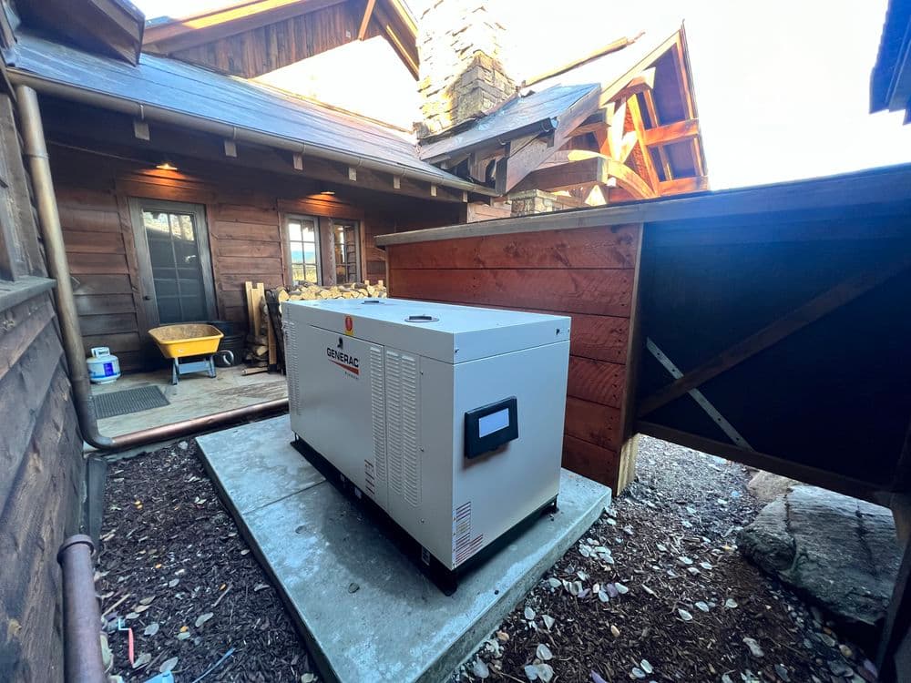 Generator installation beside wooden cabin with stone features and gravel pathway.