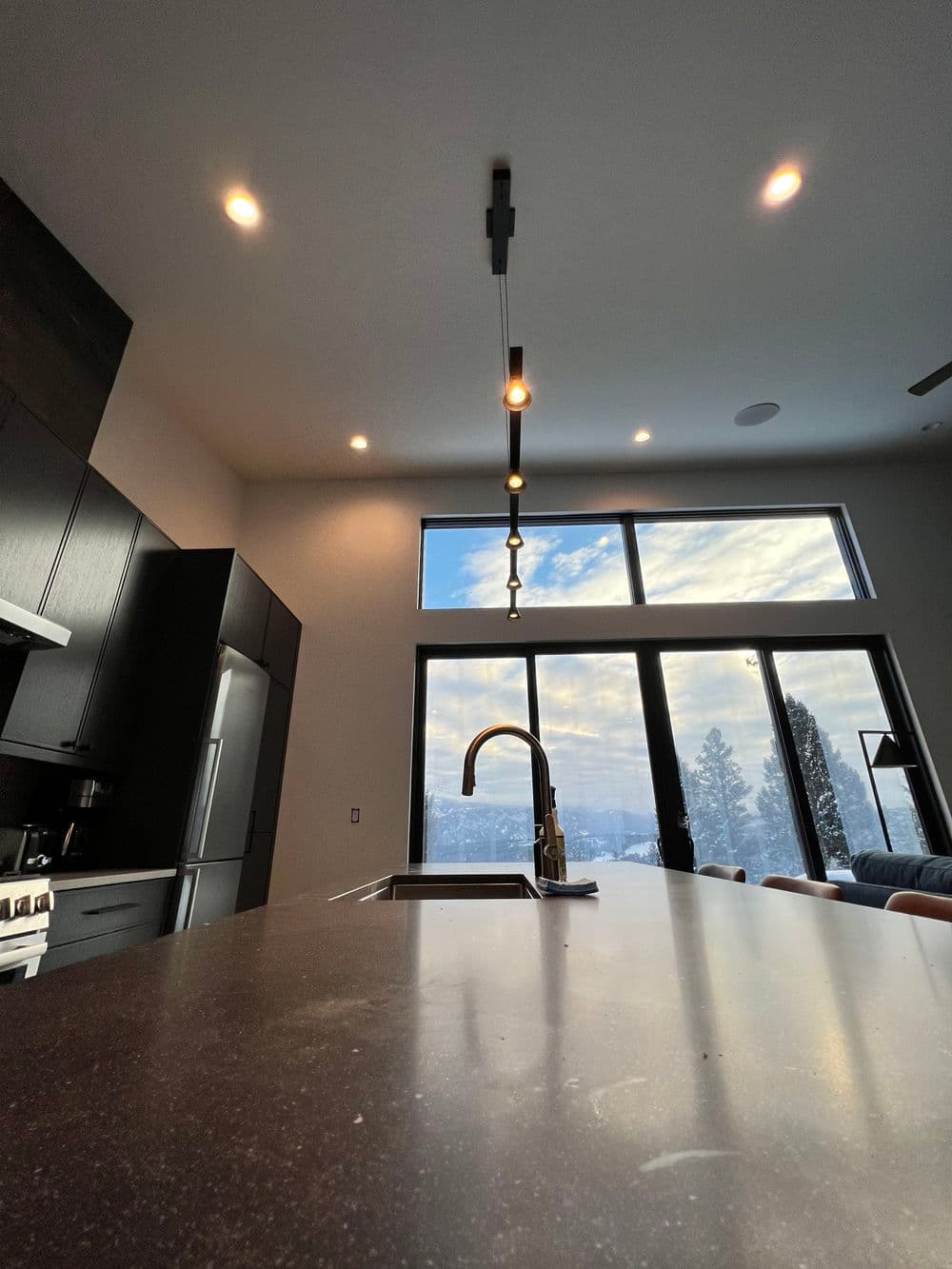 Modern kitchen with sleek design, large window view, and stylish pendant lighting.