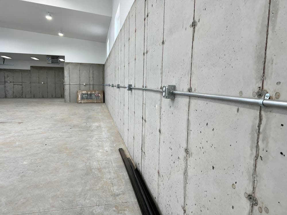 Concrete wall with metal brackets, empty interior space featuring raw industrial design elements.