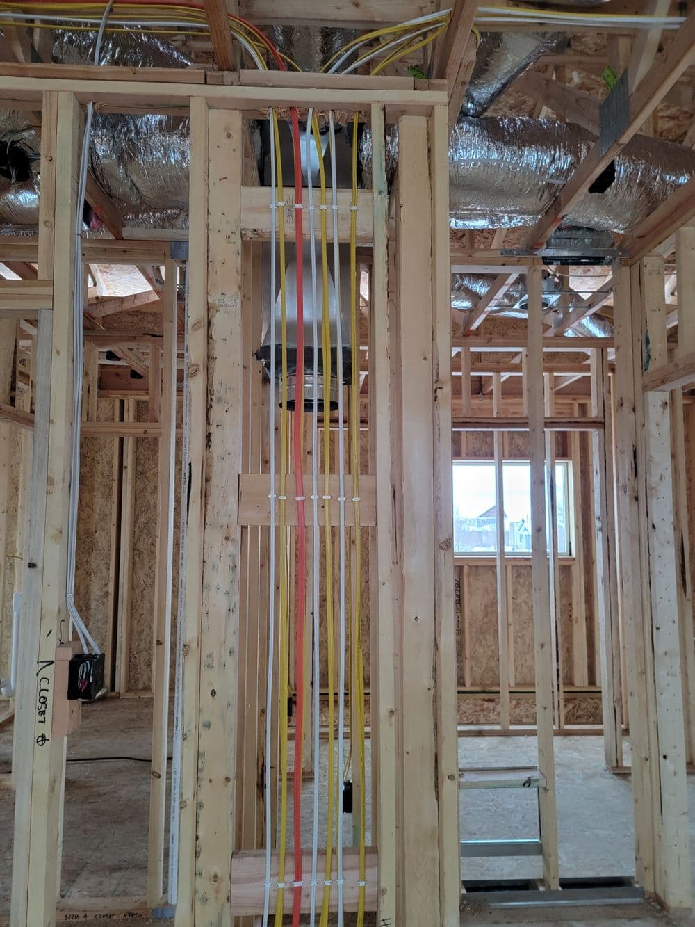 Newly constructed interior with exposed wooden framing and colorful electrical wiring.