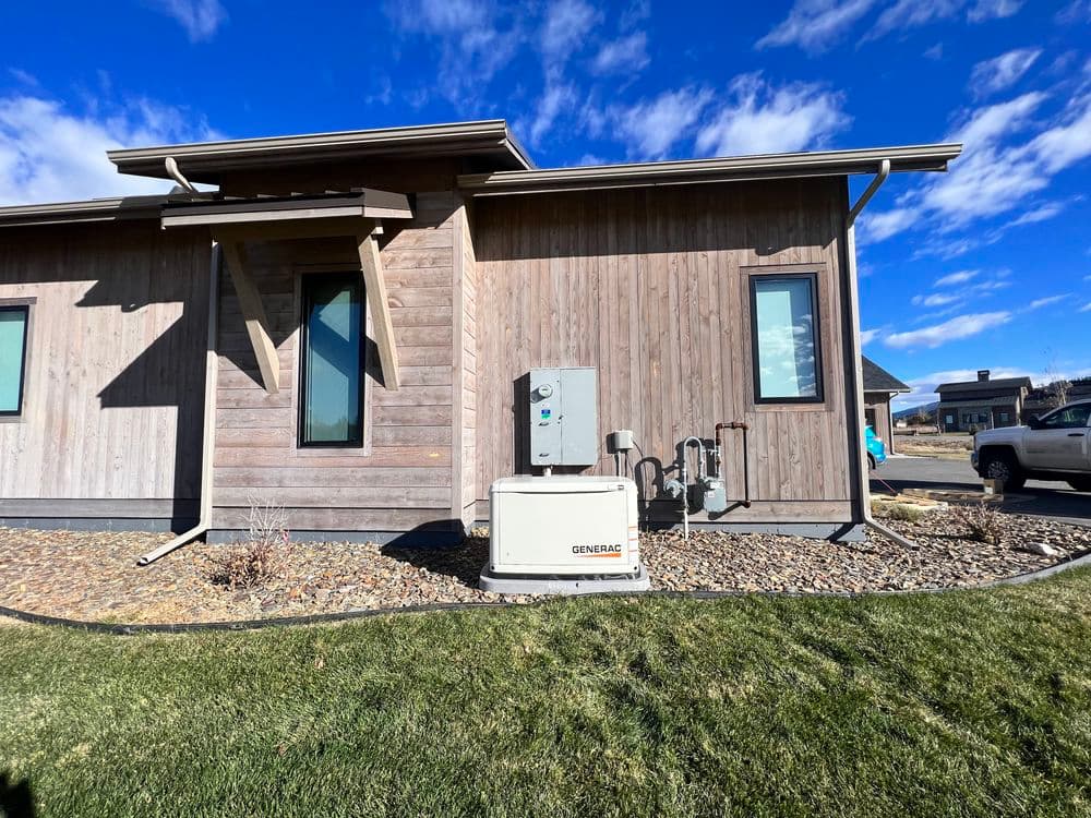 Modern home exterior with a Generac generator and utility connections in a landscaped yard.