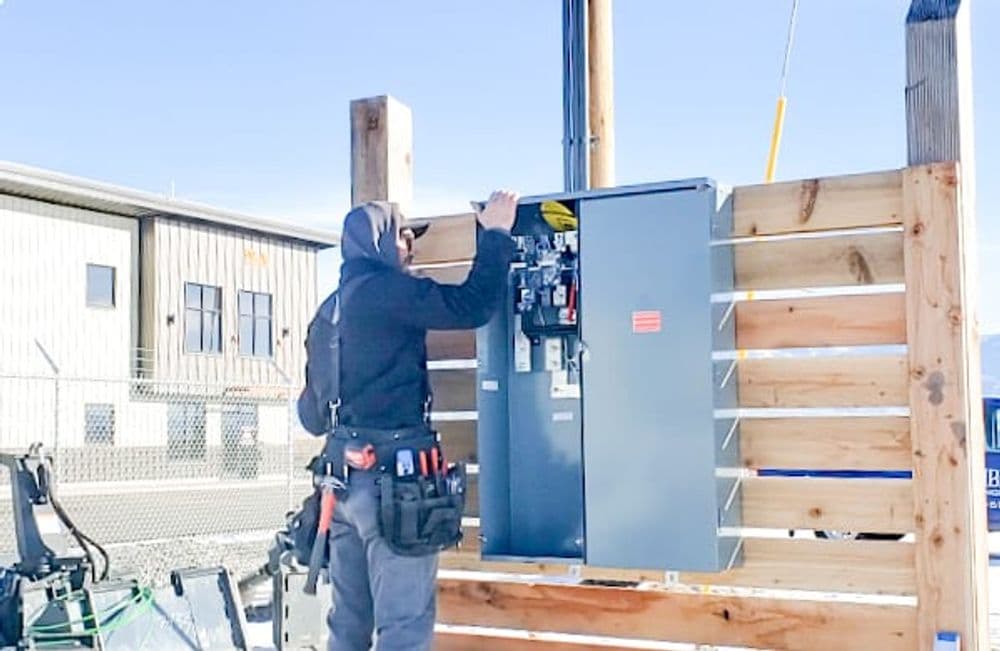 Electrician working on an electrical panel installation at a construction site.