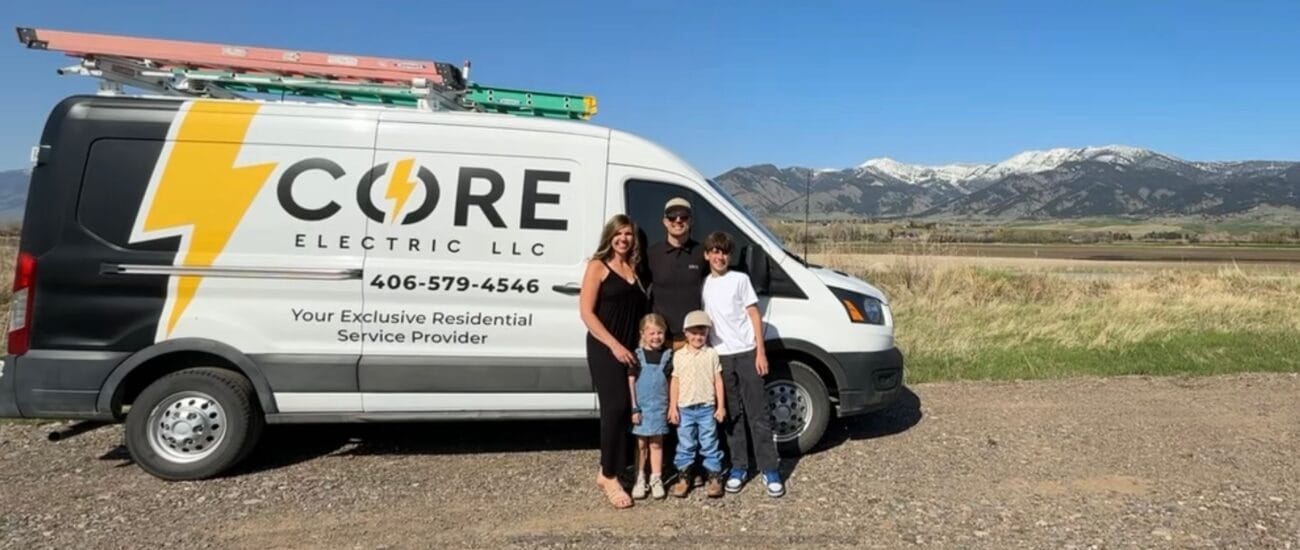 A family of five stands in front of a CORE Electric LLC van parked on a rural road, with mountains and fields in the background.